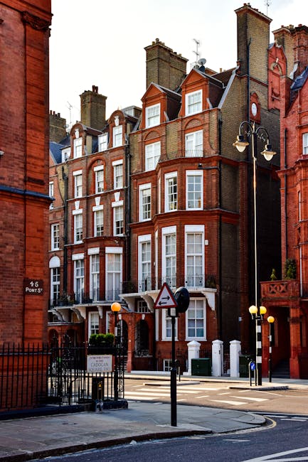 A row of terraced residential buildings with Victorian architecture in Fulham, London, featuring a combination of brick and stucco facades painted in pastel blue, cream, and vibrant green. The buildin