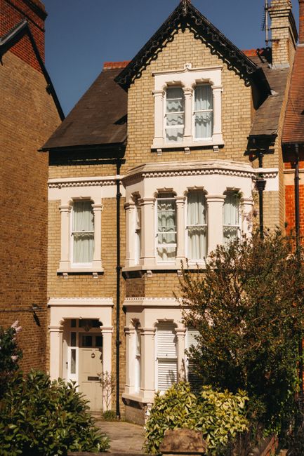 A row of Victorian-style terraced houses in Fulham, featuring colorful facades painted in shades of teal, white, blue, and pink. The buildings are three to four stories high with bay windows and decor